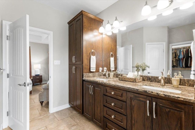 ensuite bathroom with a sink, ensuite bathroom, double vanity, and tile patterned floors