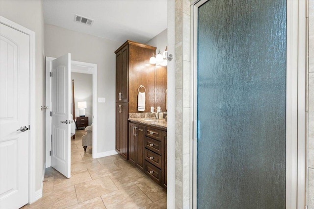 ensuite bathroom with a shower with shower door, visible vents, baseboards, and vanity