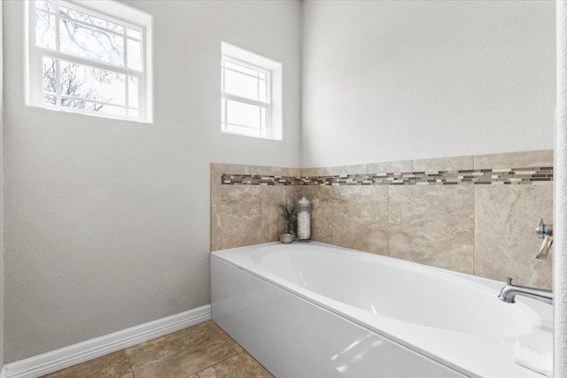 full bath featuring tile patterned flooring, a garden tub, and baseboards