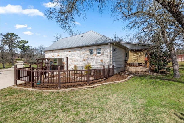 back of property with a wooden deck, stone siding, and a lawn