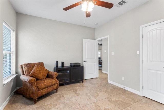 living area featuring baseboards, visible vents, and ceiling fan