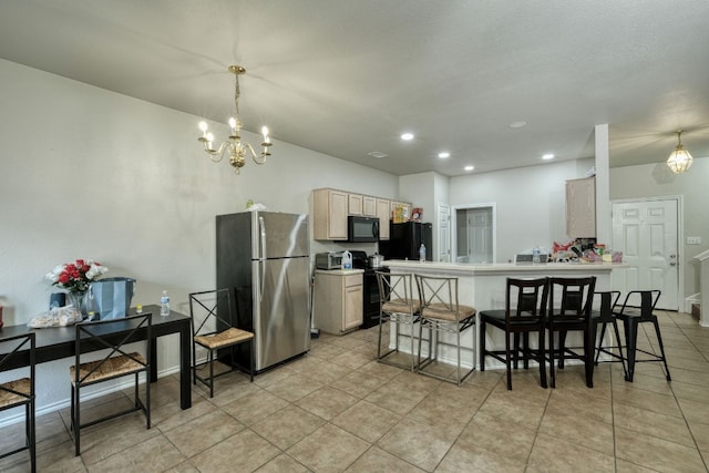 kitchen with an inviting chandelier, black appliances, a breakfast bar area, and a peninsula