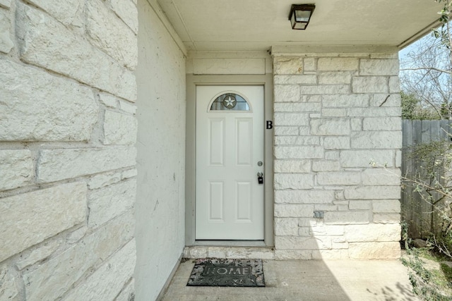 property entrance with fence and stone siding