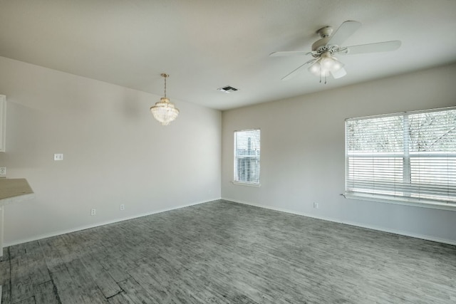 unfurnished room featuring visible vents, ceiling fan with notable chandelier, and baseboards