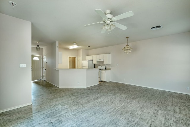 unfurnished living room featuring visible vents, ceiling fan with notable chandelier, baseboards, and wood finished floors