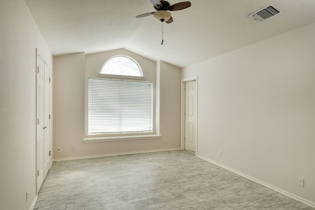 unfurnished room featuring visible vents, a ceiling fan, wood finished floors, baseboards, and vaulted ceiling