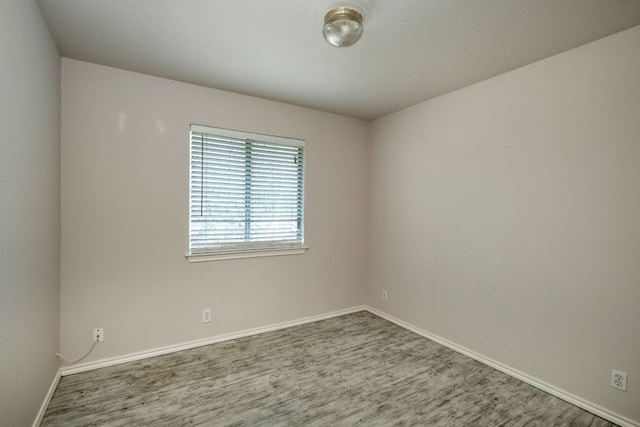 unfurnished room with baseboards and wood finished floors