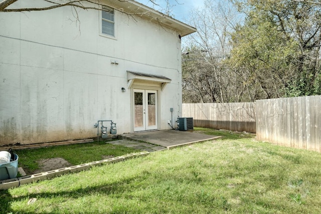 rear view of house featuring a patio, central AC unit, fence, french doors, and a lawn