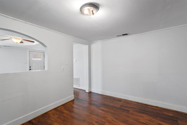 unfurnished room with arched walkways, visible vents, baseboards, and wood finished floors