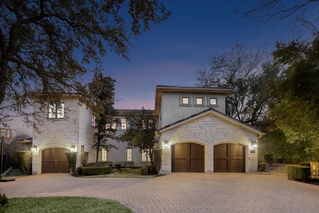 view of front of house with decorative driveway and stone siding