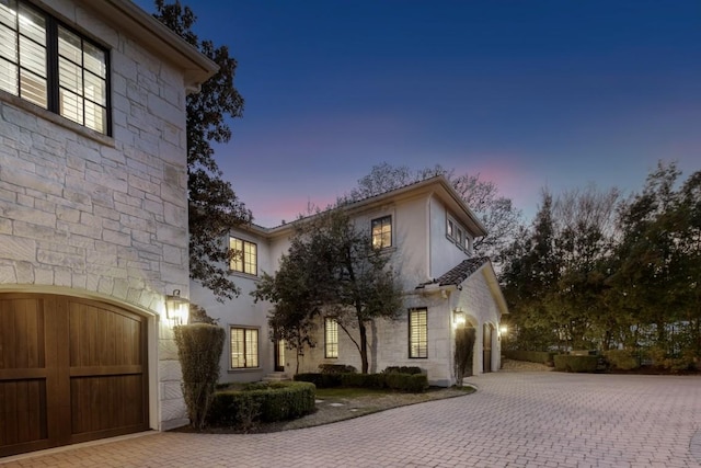 view of front of property with decorative driveway, stone siding, and a garage