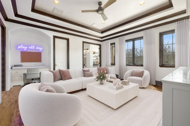 living room featuring visible vents, crown molding, a raised ceiling, and ceiling fan