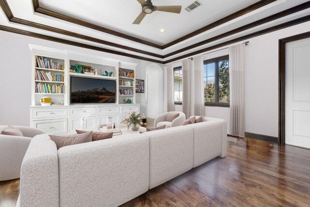 living area featuring dark wood-type flooring, visible vents, a tray ceiling, and ornamental molding