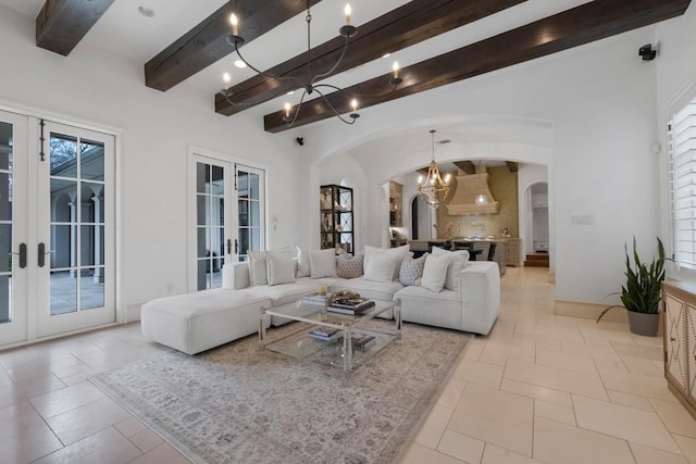 living room featuring a chandelier, beamed ceiling, a wealth of natural light, french doors, and arched walkways