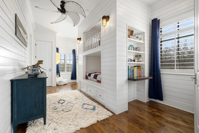 bedroom with wood walls and wood finished floors