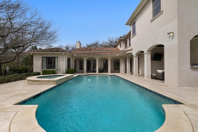 view of pool with a patio, fence, and a pool with connected hot tub