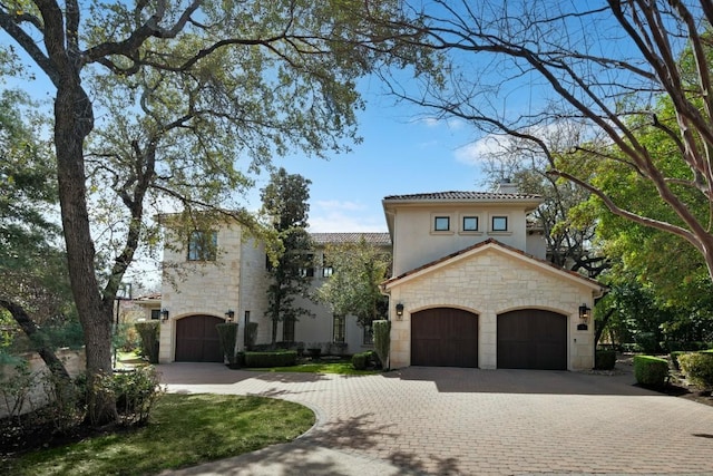 mediterranean / spanish house featuring decorative driveway, stone siding, and stucco siding