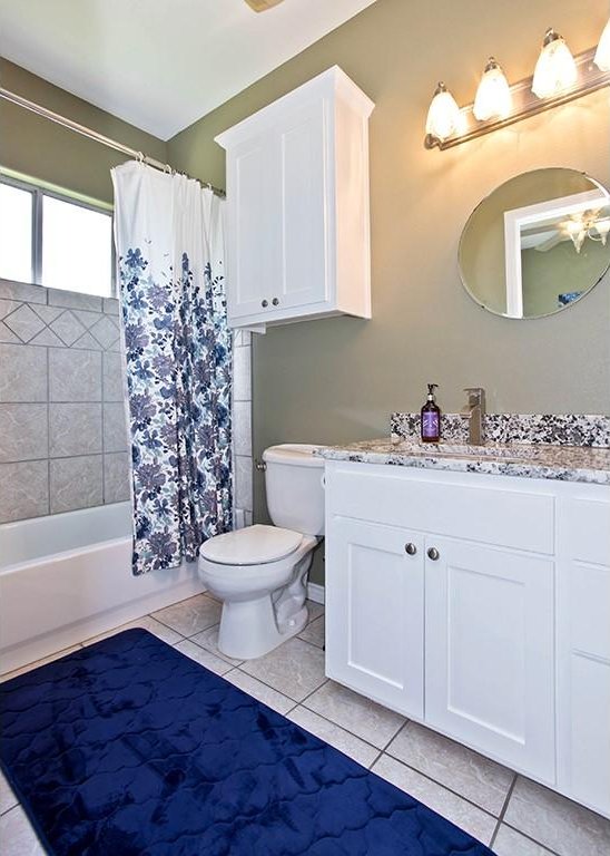 full bathroom with shower / bathtub combination with curtain, toilet, vanity, and tile patterned flooring