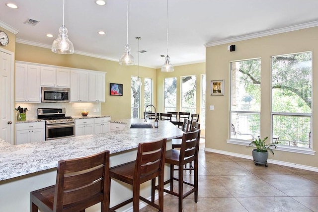 kitchen featuring a sink, tasteful backsplash, appliances with stainless steel finishes, a breakfast bar area, and crown molding