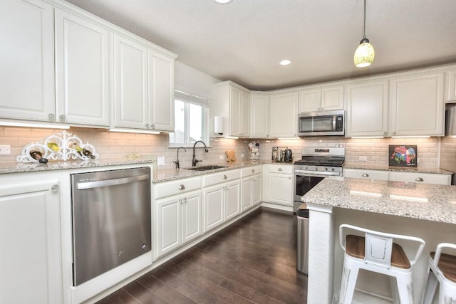 kitchen featuring dark wood finished floors, a sink, decorative backsplash, appliances with stainless steel finishes, and white cabinetry