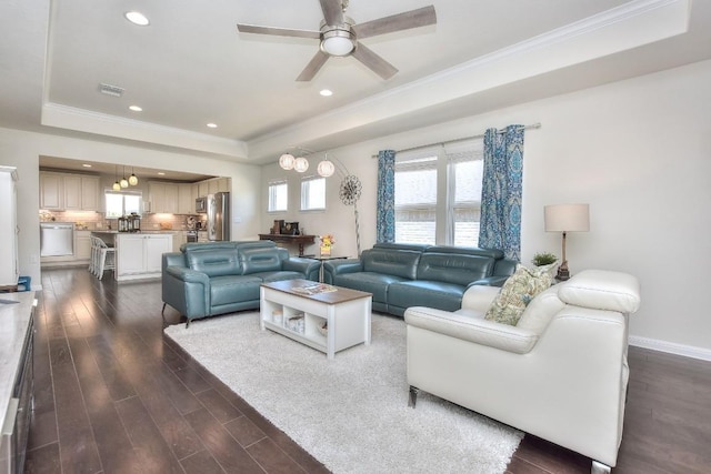 living area featuring dark wood finished floors, crown molding, a raised ceiling, and a ceiling fan