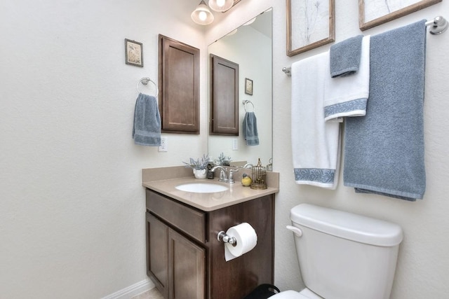 half bath featuring toilet, vanity, and baseboards