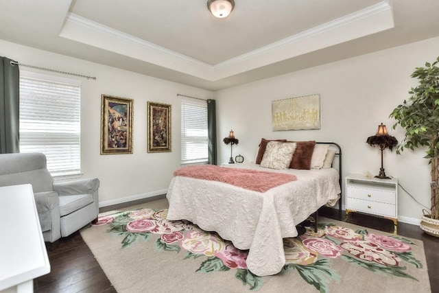 bedroom featuring dark wood finished floors, a tray ceiling, crown molding, and baseboards