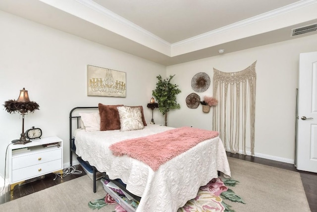 bedroom with visible vents, baseboards, wood finished floors, and crown molding