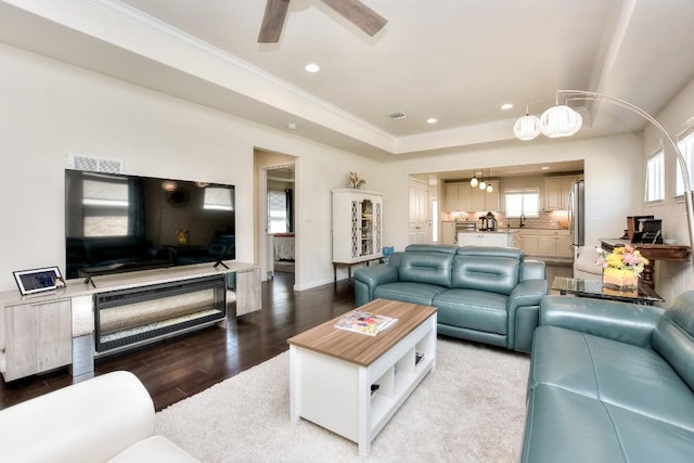 living area featuring crown molding, wood finished floors, visible vents, and ceiling fan