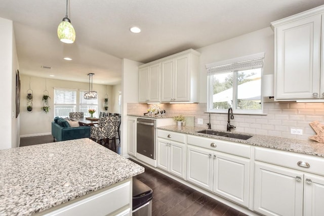 kitchen featuring dark wood-style floors, plenty of natural light, a sink, white cabinetry, and backsplash