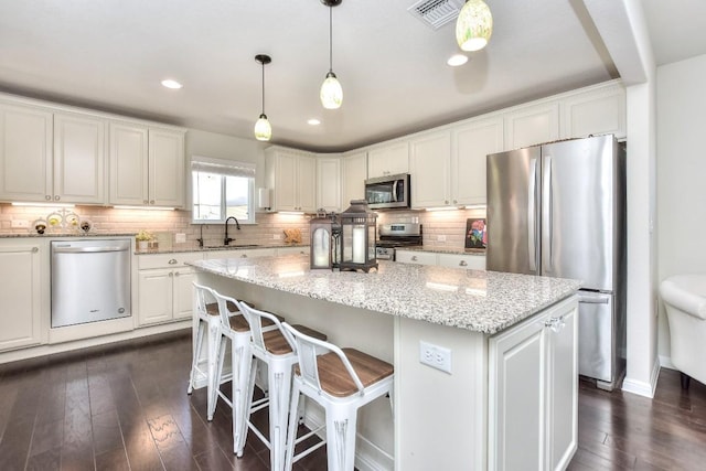 kitchen with visible vents, a sink, a center island, appliances with stainless steel finishes, and white cabinets