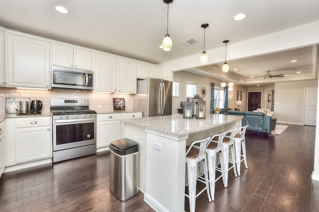 kitchen with visible vents, decorative backsplash, appliances with stainless steel finishes, white cabinetry, and a raised ceiling