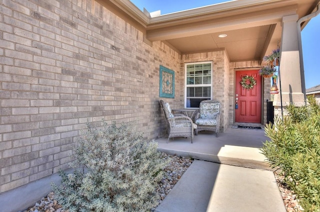 view of exterior entry featuring brick siding and a porch