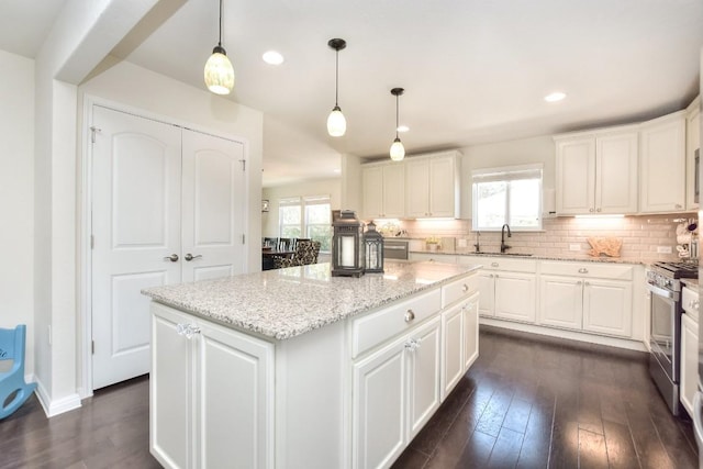 kitchen featuring stainless steel gas range oven, decorative backsplash, a center island, and a sink