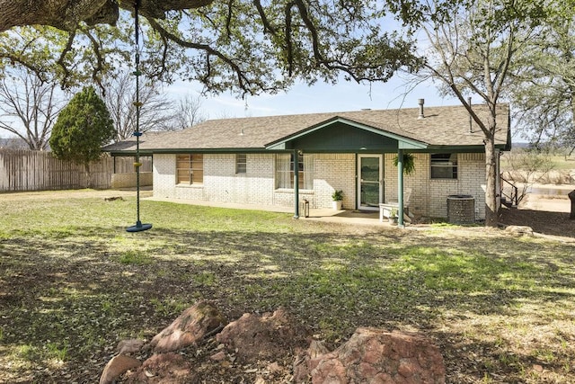 back of house with a yard, brick siding, central AC unit, and fence