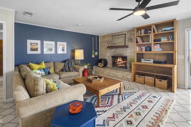 living area featuring crown molding, a brick fireplace, a ceiling fan, and visible vents