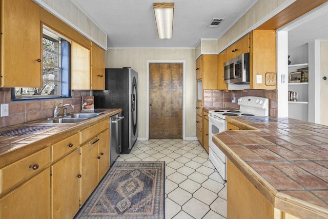 kitchen featuring tile countertops, visible vents, a sink, appliances with stainless steel finishes, and backsplash