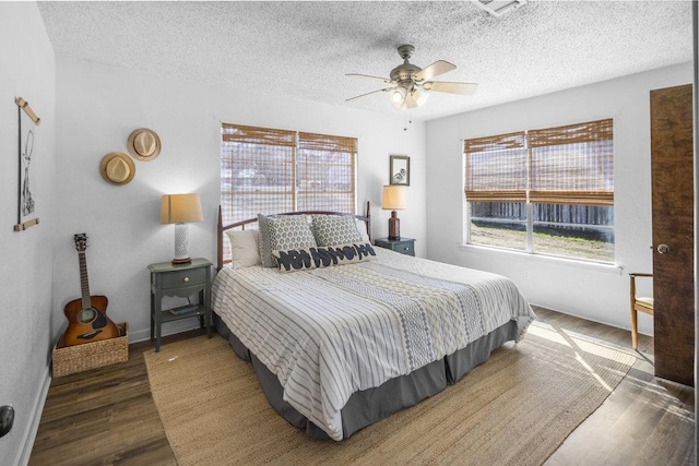 bedroom featuring baseboards, a textured ceiling, wood finished floors, and a ceiling fan