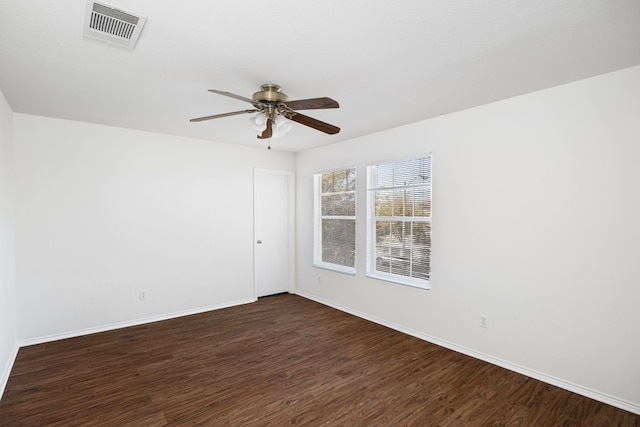 empty room featuring visible vents, baseboards, ceiling fan, and dark wood finished floors