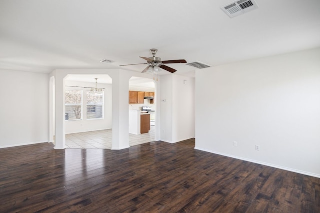 unfurnished living room featuring wood finished floors, ceiling fan with notable chandelier, and visible vents