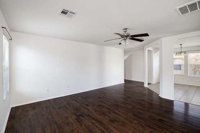 spare room featuring wood finished floors, ceiling fan with notable chandelier, visible vents, and baseboards