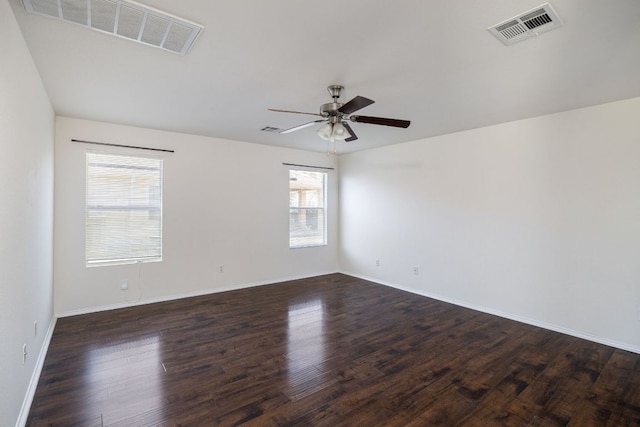 spare room featuring baseboards, visible vents, dark wood-style flooring, and ceiling fan