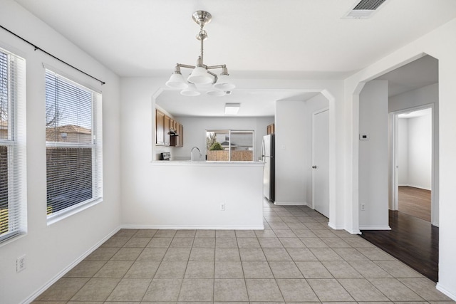 interior space with light tile patterned floors, baseboards, visible vents, a sink, and a notable chandelier