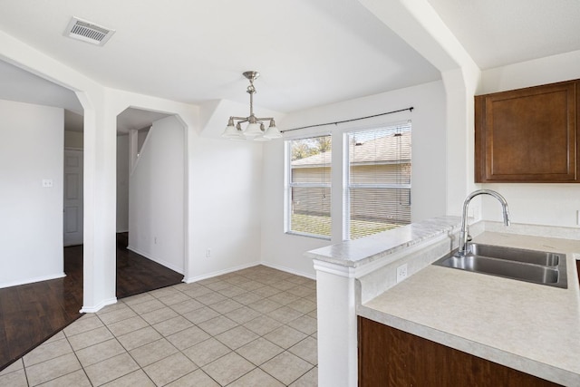 unfurnished dining area with visible vents, a sink, an inviting chandelier, light tile patterned flooring, and baseboards