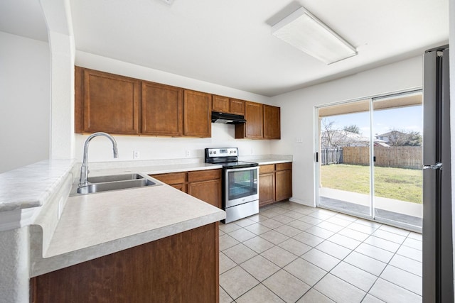 kitchen featuring a sink, under cabinet range hood, stainless steel appliances, light tile patterned flooring, and light countertops