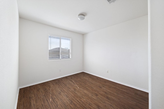 spare room with baseboards and dark wood-style floors