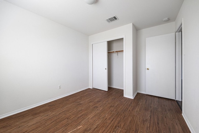 unfurnished bedroom featuring dark wood-style floors, visible vents, a closet, and baseboards