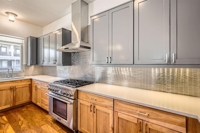 kitchen featuring a sink, dark wood-style floors, wall chimney exhaust hood, decorative backsplash, and high end range