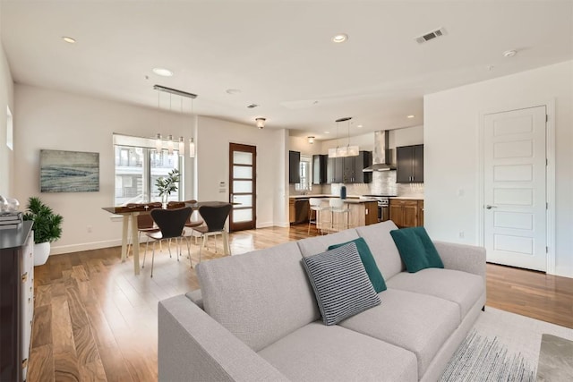 living room featuring light wood finished floors, visible vents, recessed lighting, and baseboards