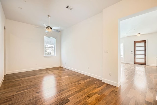 empty room with visible vents, wood finished floors, baseboards, and ceiling fan